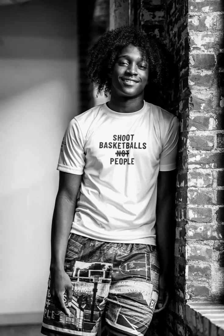 A young SBNP player smiling in a Shoot Basketballs NOT People shirt